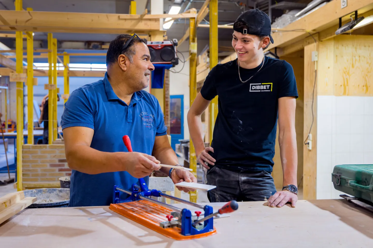 Student en docent snijden tegels