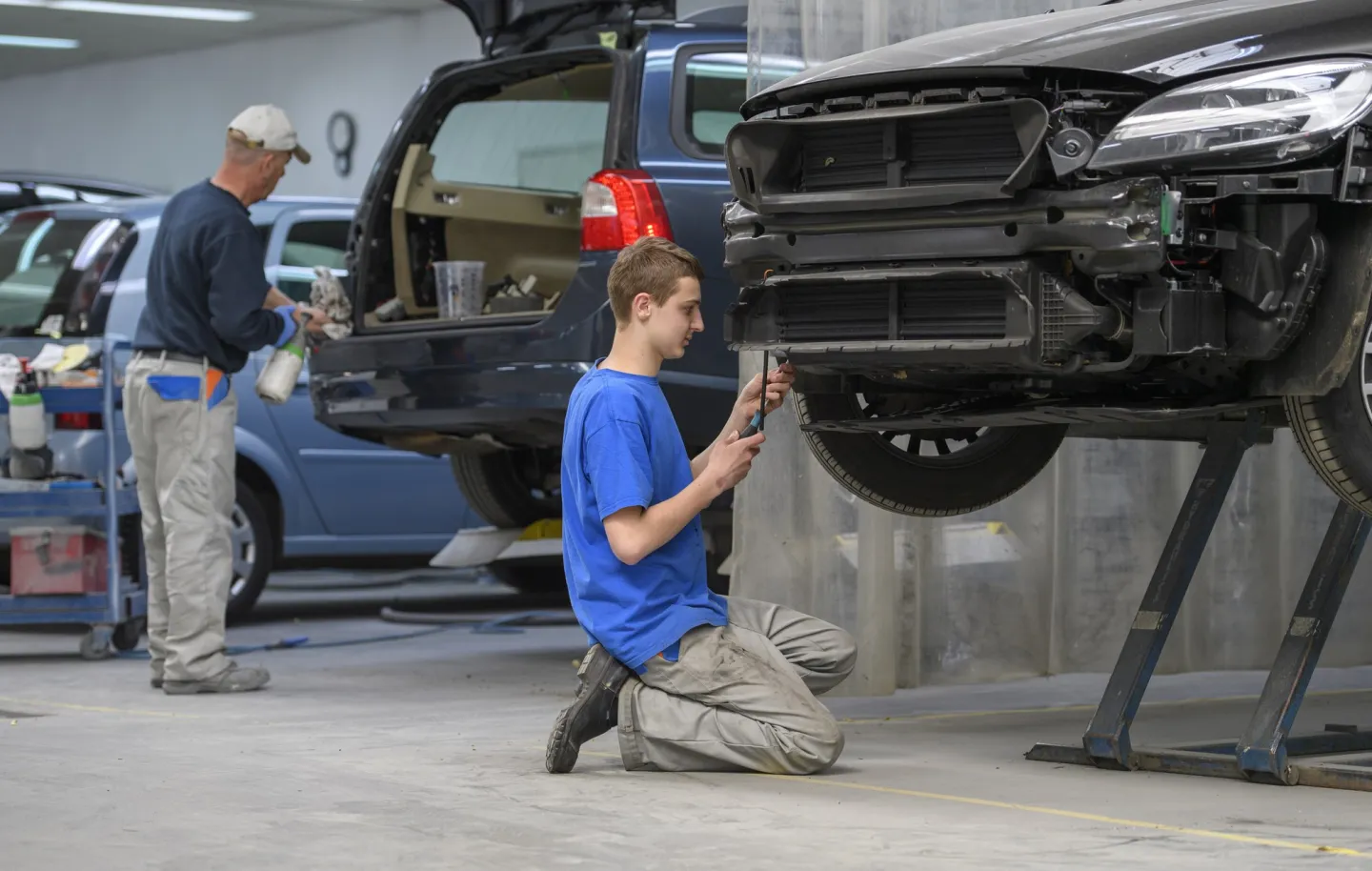 Student werkt met gereedschap aan beschadigde auto