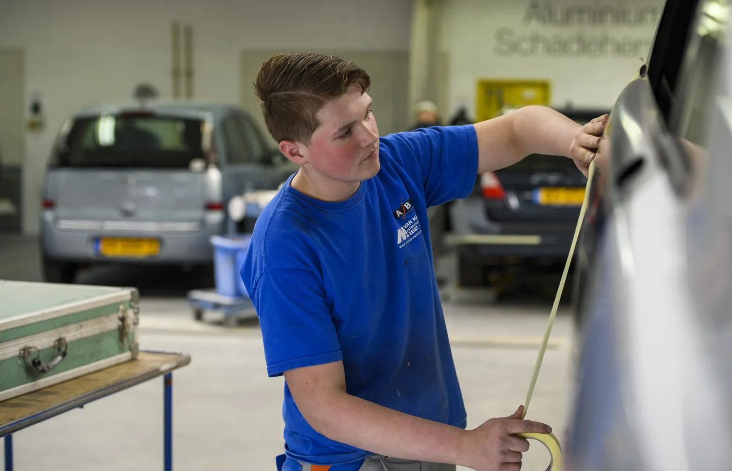 Student herstelt schade aan een auto met gereedschap in de werkplaats