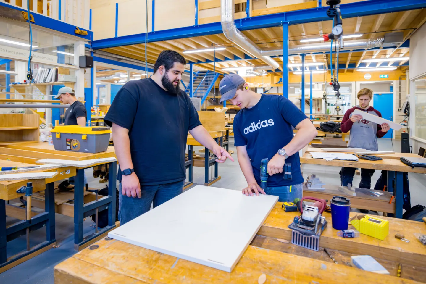 Docent en student bekijken samen hout project