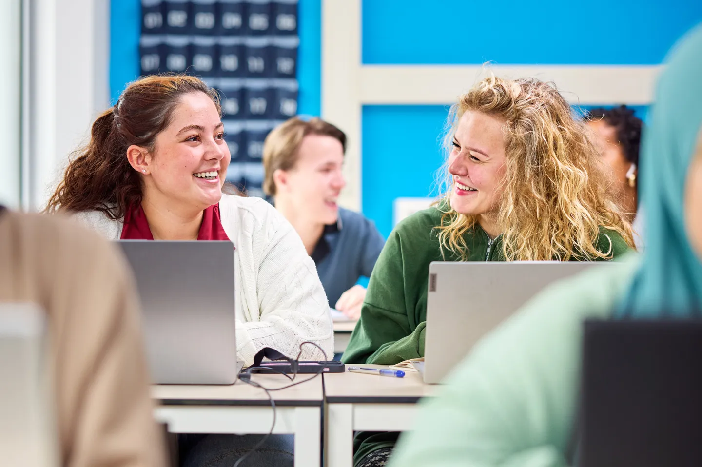 Studenten lachen en werken achter laptop in de klas