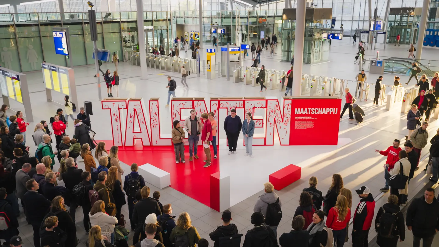 Foto van de actie in de hal van centraal station met grote letters het woord talenten