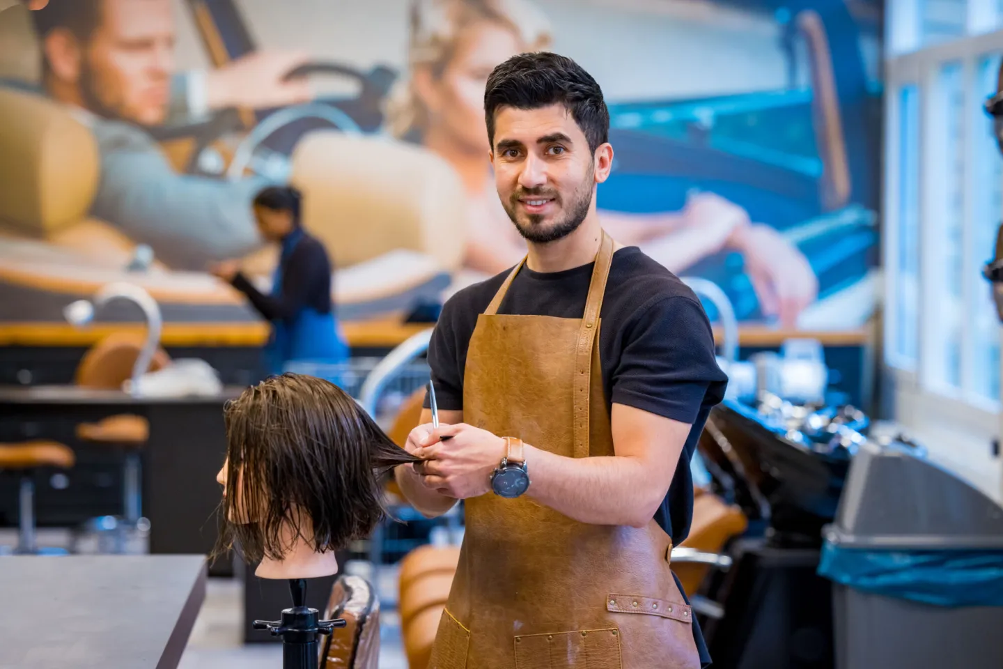 Een man in een schort knipt haar in een salon.