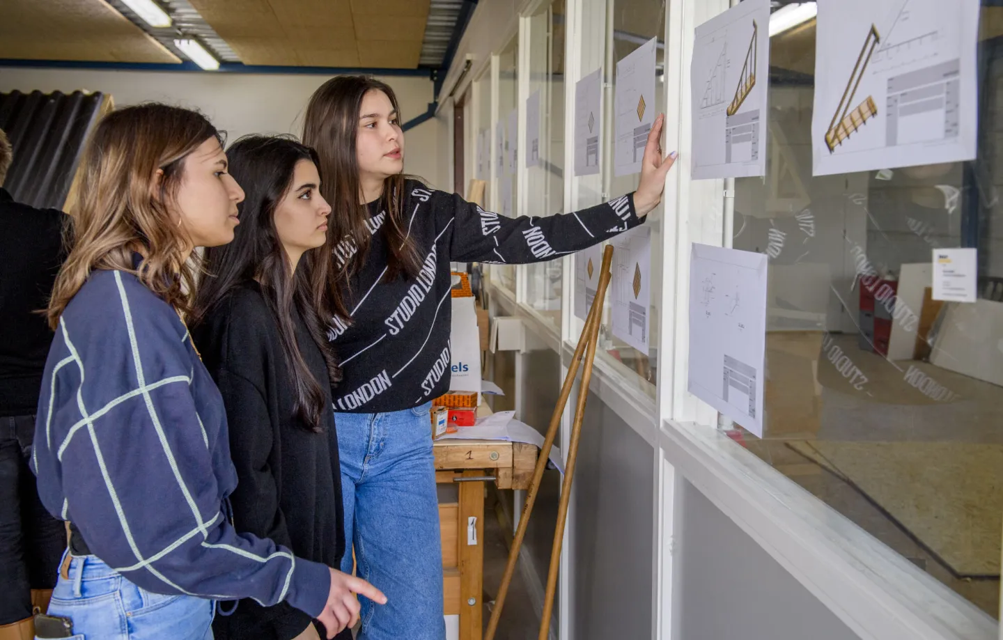 Drie studenten lezen werktekening tijdens project