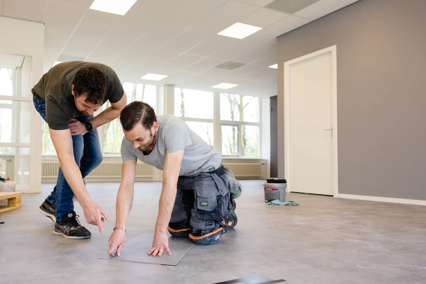 Docent begeleidt student Allound Interieurvakman Woningstofferen bij het leggen van vloeren 