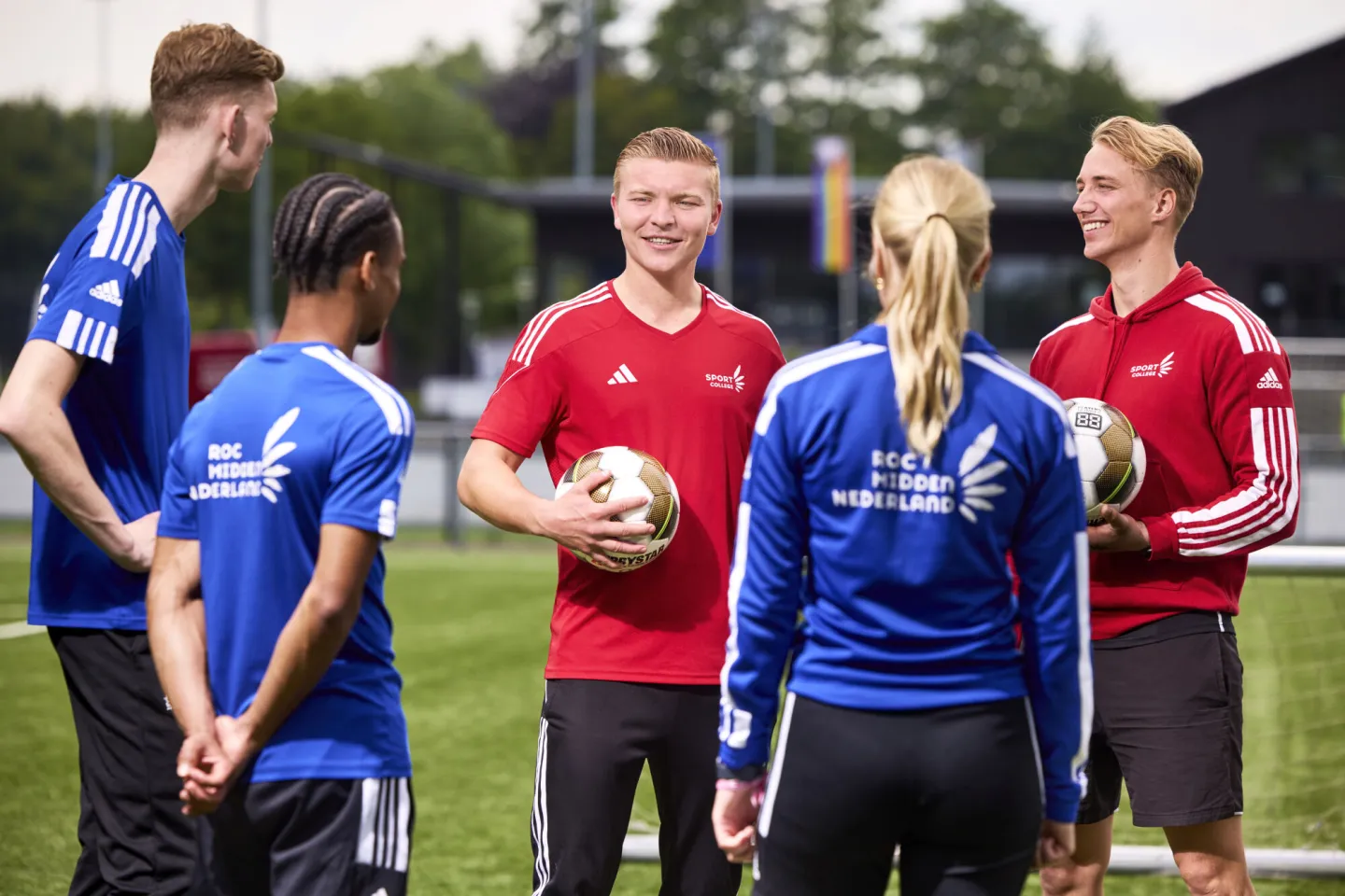 Docenten geven les aan studenten op het sportveld