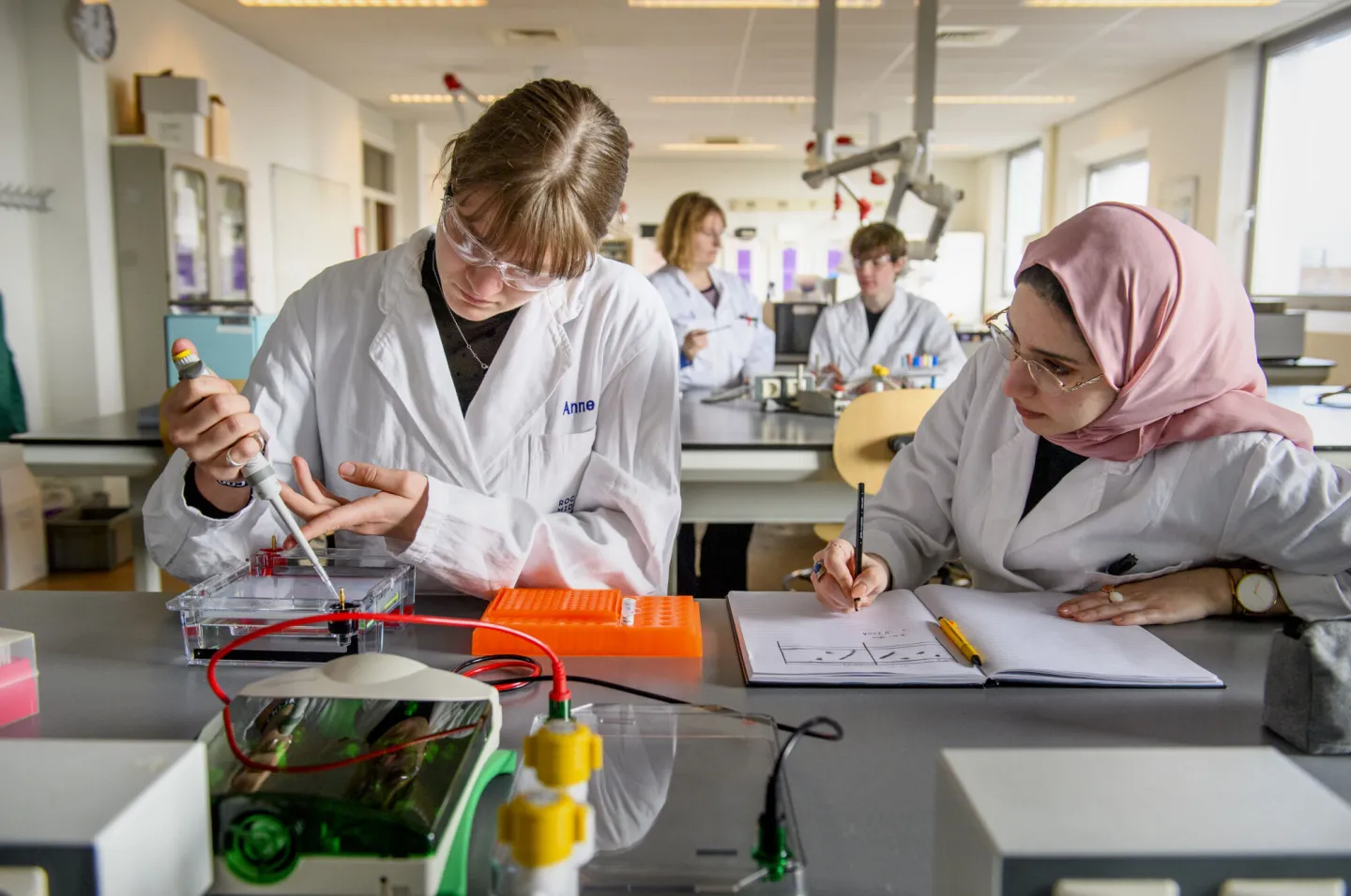 Twee vrouwen in laboratoriumjassen werken aan een project.