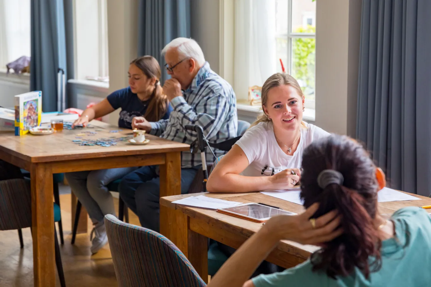 Een groep mensen zit aan een tafel in een eetkamer.