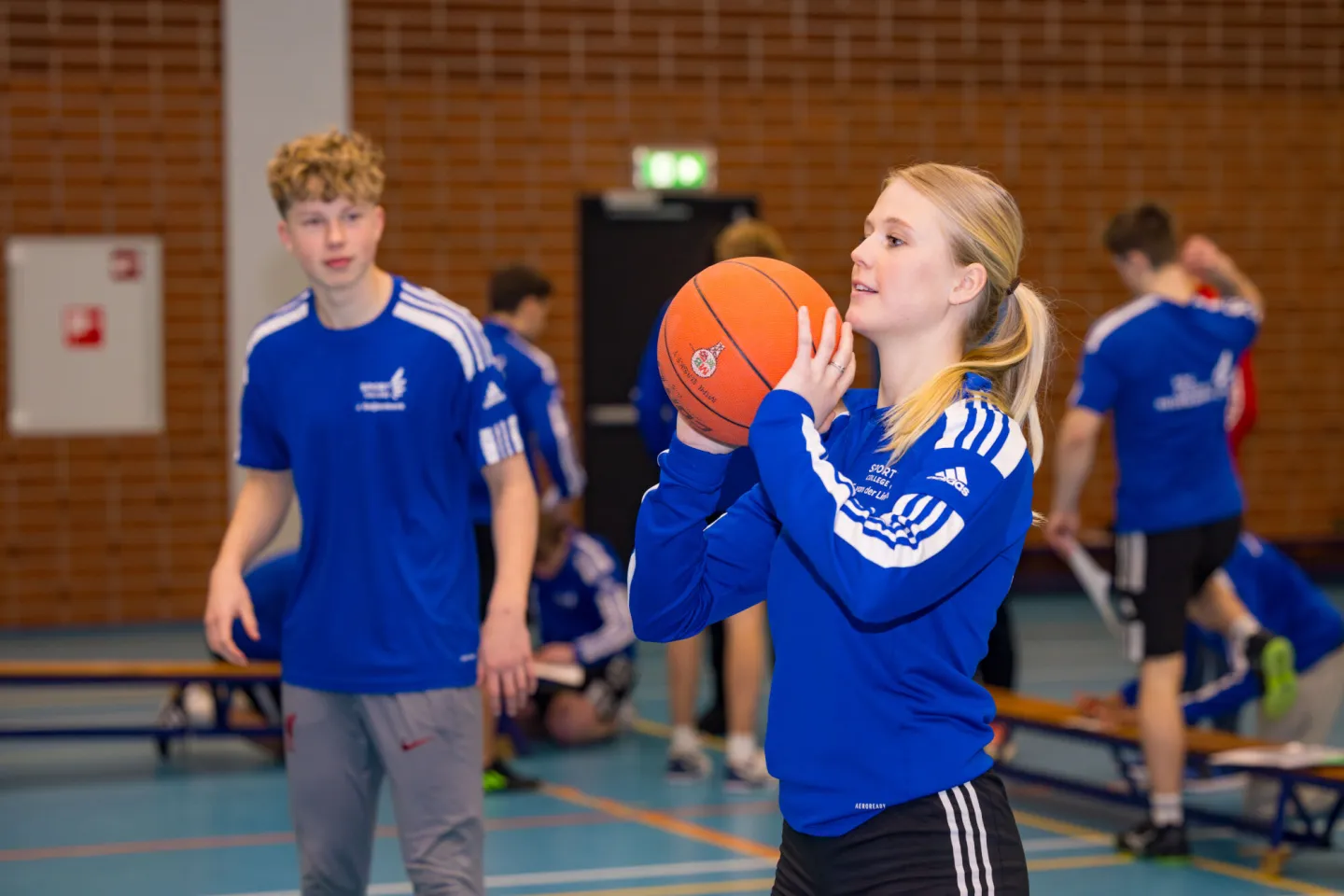 Meisje draagt een blauw shirt en houdt een basketbal vast.