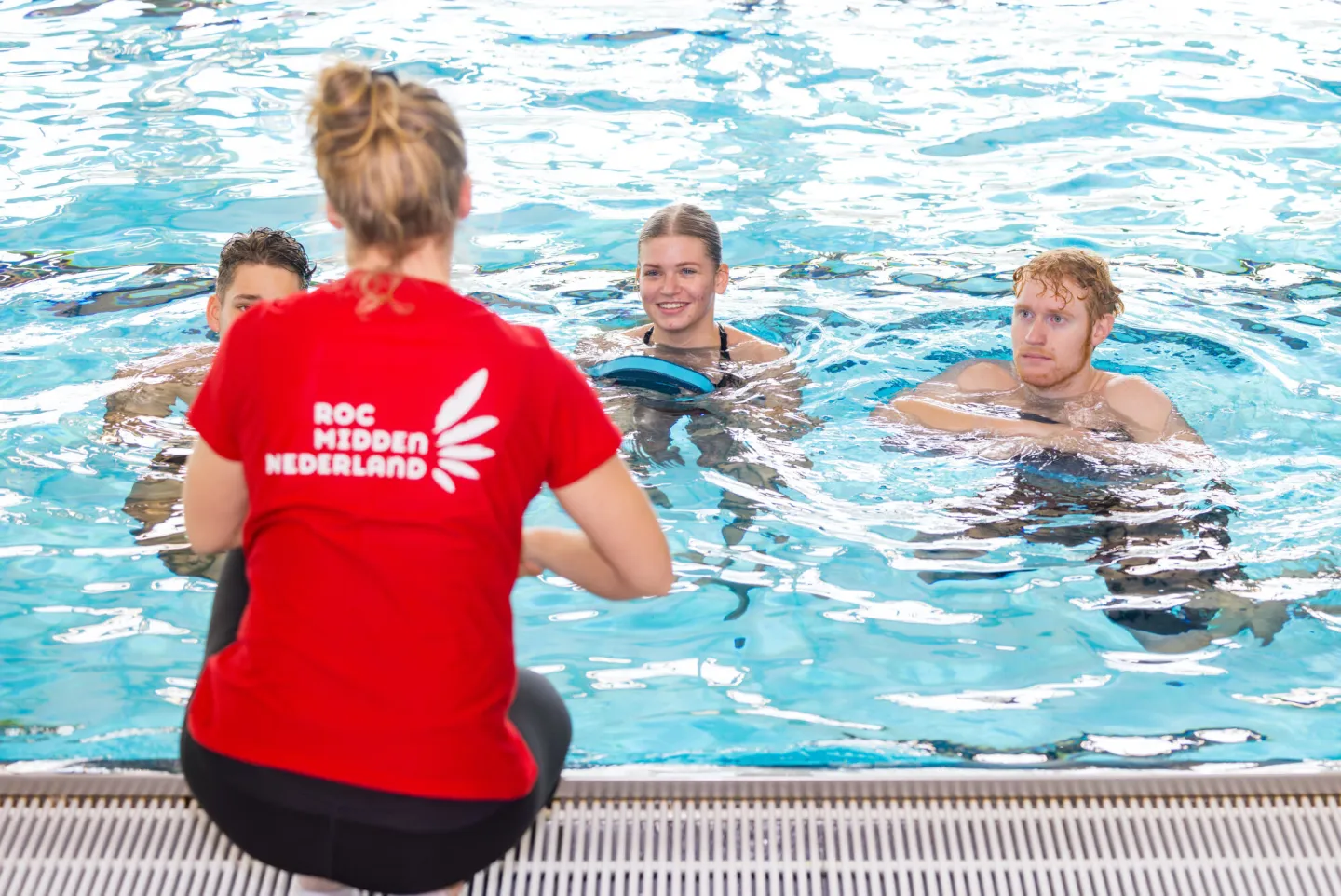 Zwemlessen in het zwembad: jonge mensen leren zwemmen onder begeleiding van een sportinstructeur.