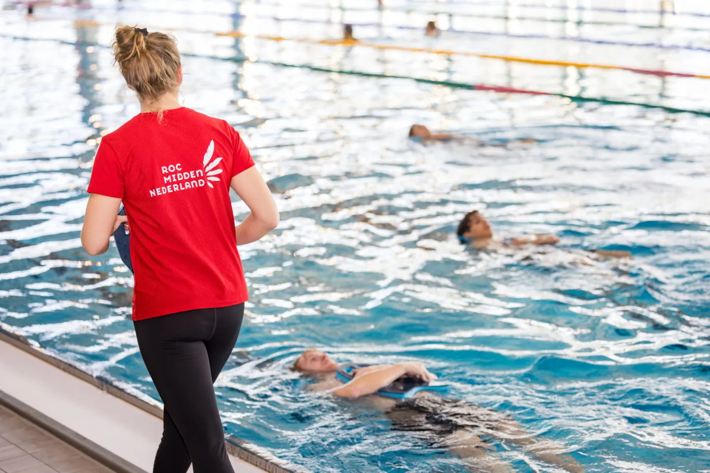 Professionele instructeur leert jonge mensen zwemmen in het zwembad.