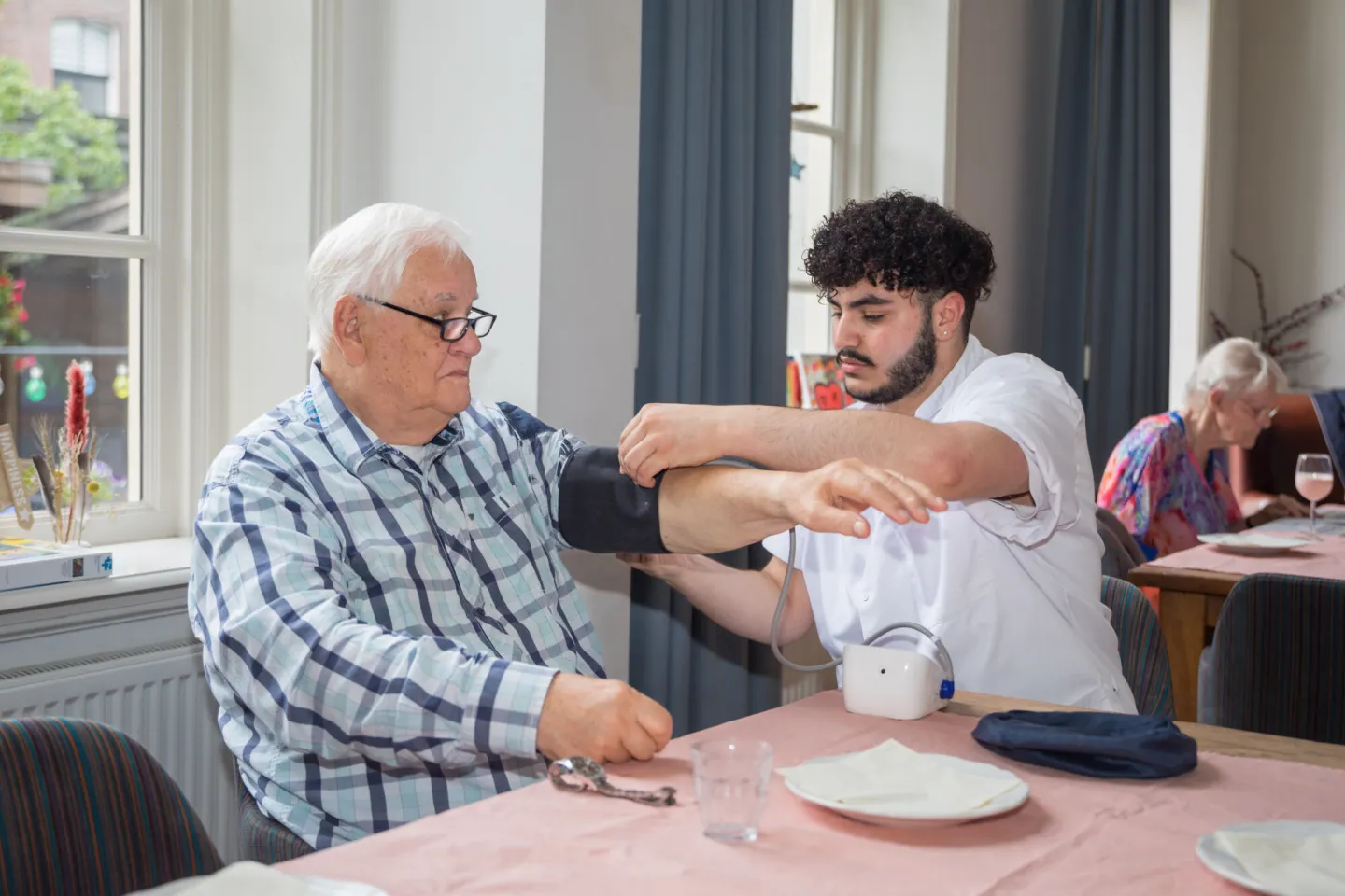 Een man krijgt zijn bloeddruk gecontroleerd door een verpleger