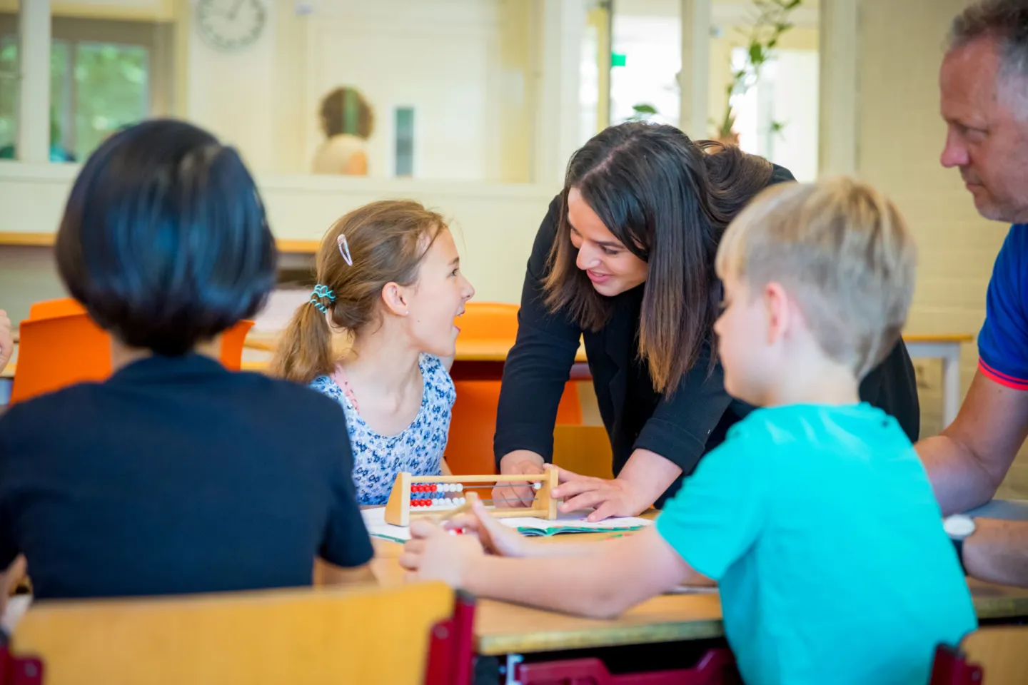 Een leraar helpt kinderen met hun werk in een klaslokaal. 