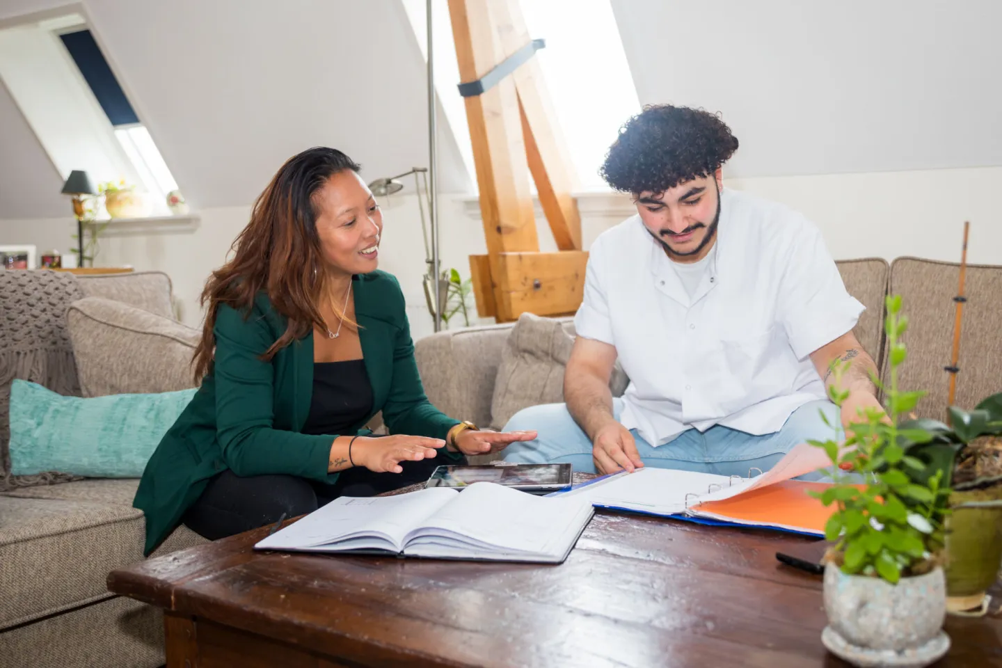 Een man en vrouw zitten aan een tafel met documenten en overleggen met elkaar