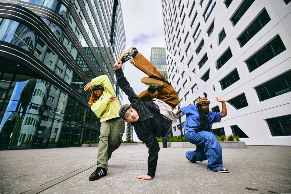 Drie dansers nemen een pose aan, tussen gebouwen bij het gemeentehuis van Utrecht