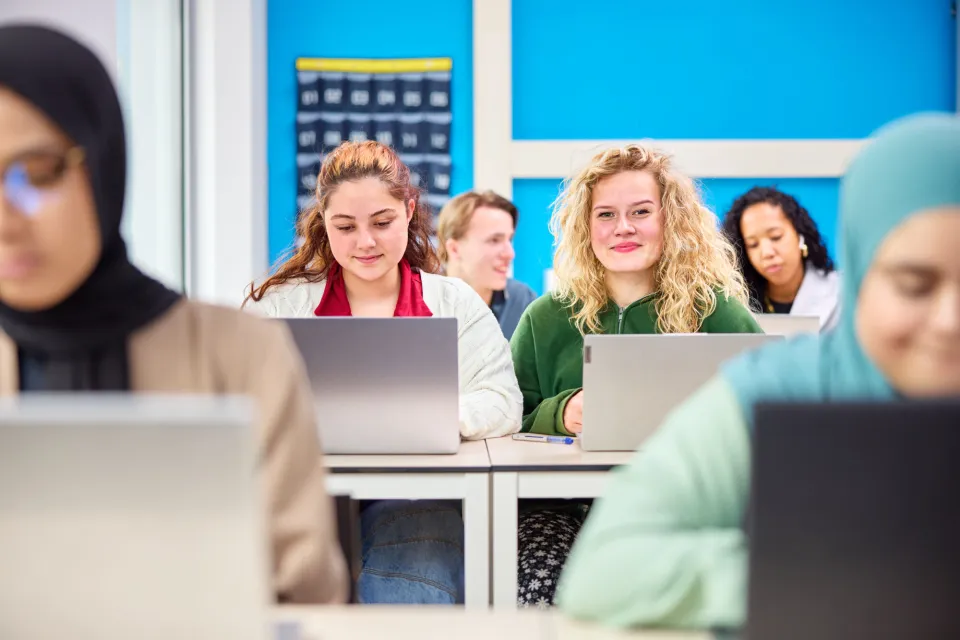 studenten zitten in de klas te werken achter hun laptop