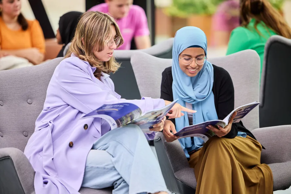 twee studiekiezers bladeren in een studiekeuzegids om te kijken welke mogelijkheden er zijn