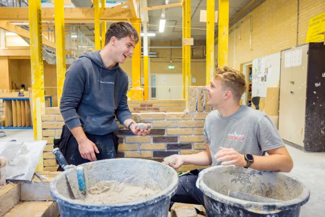 Studenten werken samen aan het metselen van een muurtje