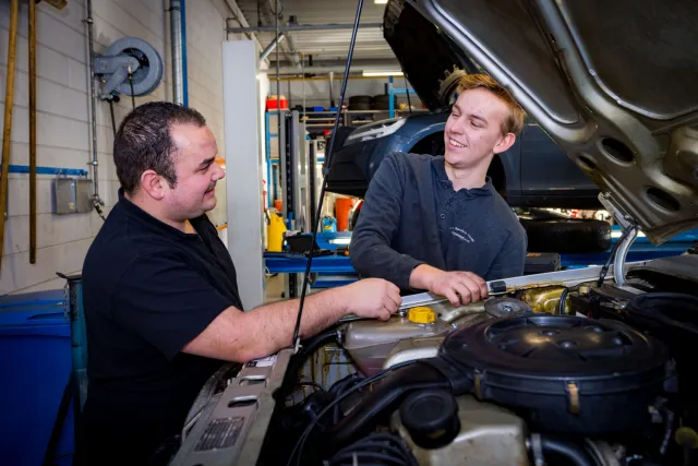 Student sleutelt aan auto met docent in garage