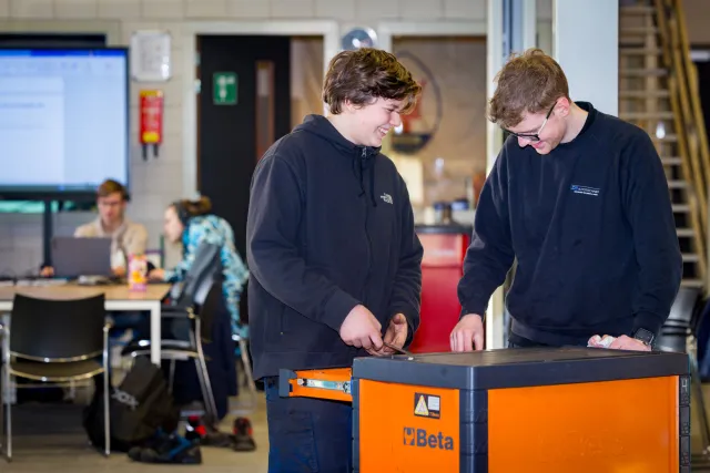 Studenten herstellen samen een auto door gebruik te maken van gereedschap