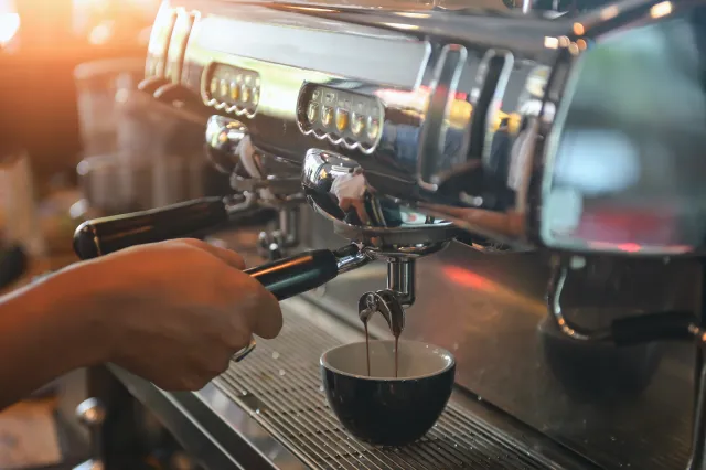 Barista zet koffiepistool in espressomachine.