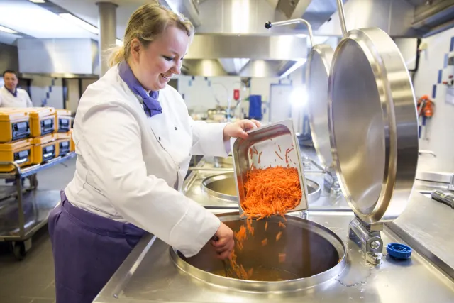 Een kok is aan het koken in de kombuis.