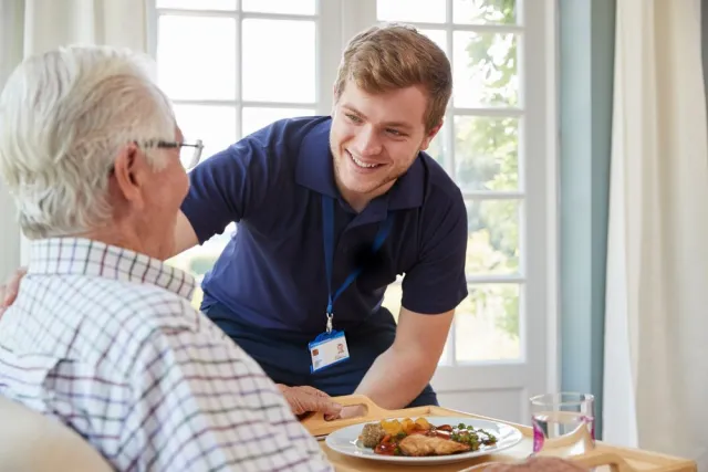 Student checkt de Positieve Gezondheid bij een cliënt die in een stoel zit.