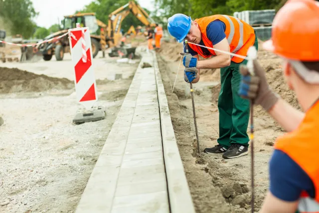 Student Allround Straatmaker controleert of straat recht wordt gelegd met gereedschap 