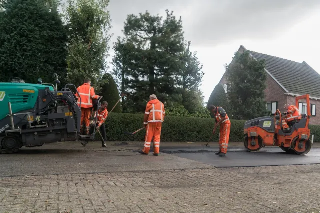 Groepje asfaltafwerkers werken samen aan de weg 