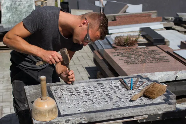 Een student die met focus een stenen monument uithakt.