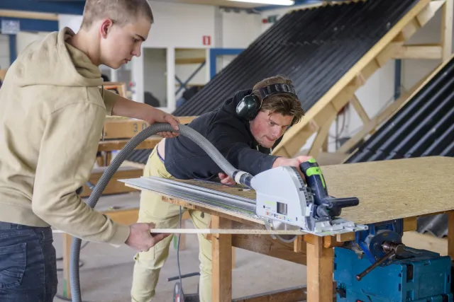 Student van de opleiding Timmerman werkt aan hout project in de werkplaats.