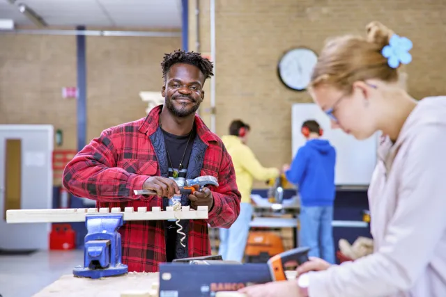 Student aan opleiding Werkvoorbereider werkt aan de bouw van een groot object van hout.