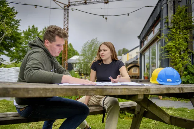 Werkvoorbereider gespecialiseerde aannemerij aan het werk op de bouwplaats met collega.