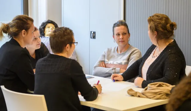 Vijf deelnemers van training BIG herregistratie Klinisch redeneren in gesprek in leslokaal. 