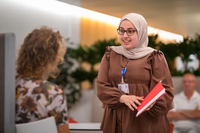 Een vrouw met hijab praat met een andere vrouw.