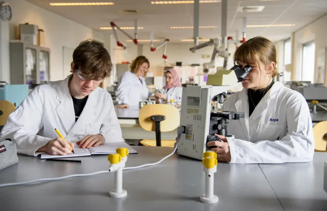 Twee studenten in laboratoriumjassen werken aan een project.