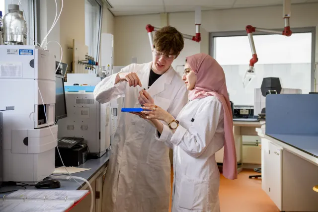 Twee personen in laboratoriumjassen doen een test in een proeflokaal.