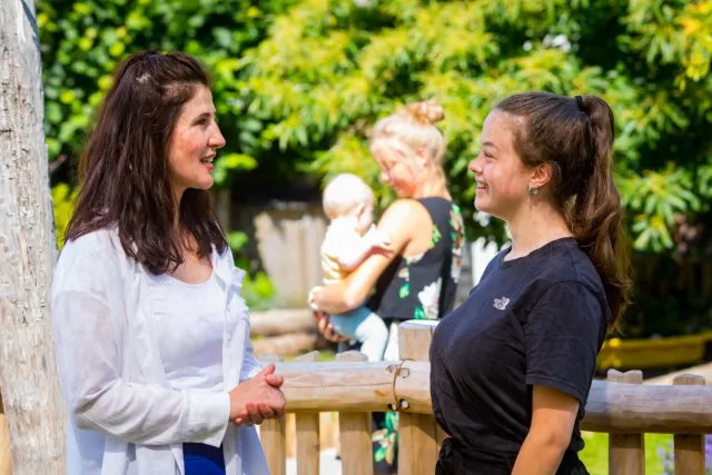 Twee pedagogisch medewerkers in gesprek buiten bij kinderdagverblijf 