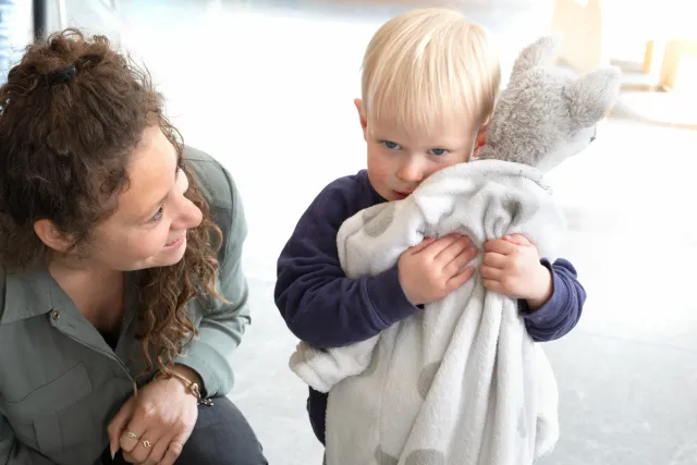 Pedagogisch medewerker is met een klein kind bezig op de dagopvang