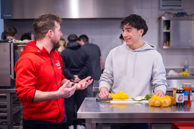 Twee mannen praten met elkaar in een keuken.