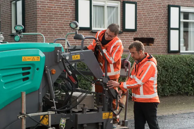 Studenten Balkman werken samen op een machine aan de weg 