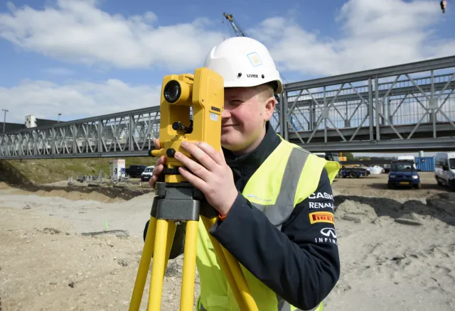 Student Infra werkt buiten met landmeter 