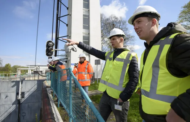 Studenten werken samen op een brug en dragen hesjes voor de veiligheid 