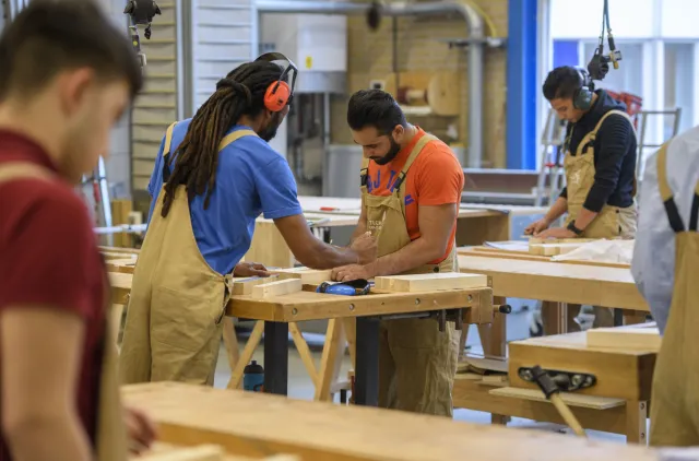 Studenten werken samen in de werkplaats aan houtprojecten