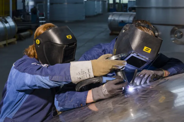 Twee studenten in de werkplaats zijn bezig met plaatwerk 