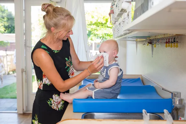 pegagogisch medewerker met certificaat aan het werk met een baby.