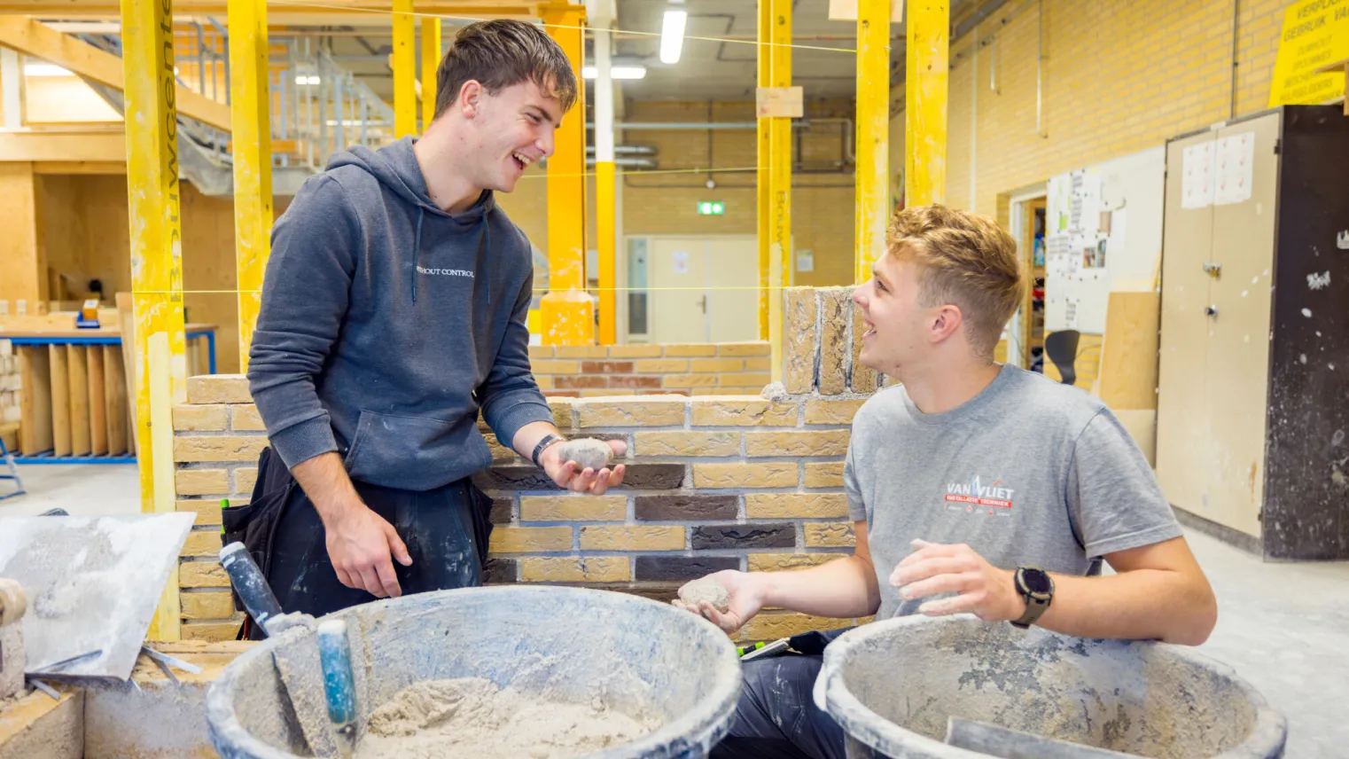 Studenten werken samen aan het metselen van een muurtje