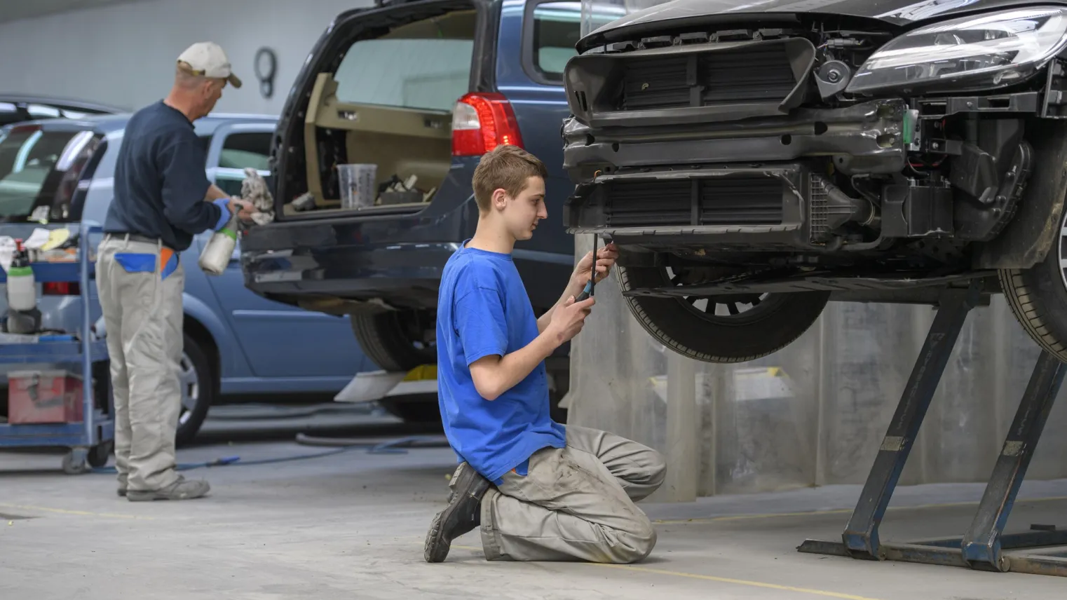 Student werkt met gereedschap aan beschadigde auto