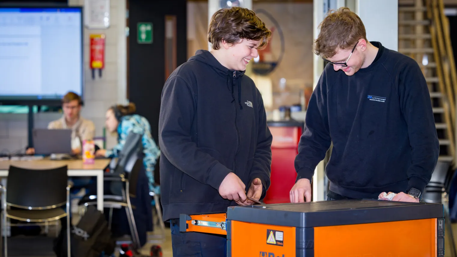 Studenten herstellen samen een auto door gebruik te maken van gereedschap