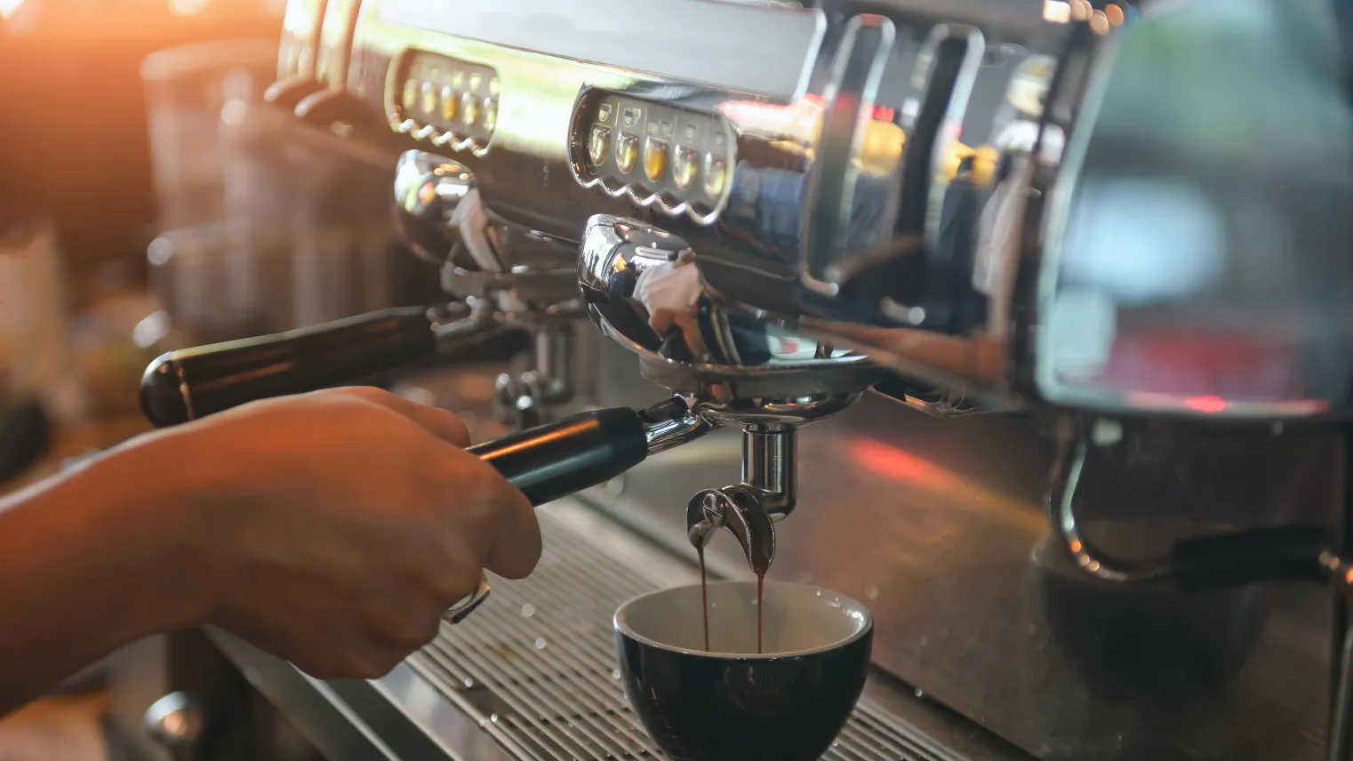 Barista zet koffiepistool in espressomachine.